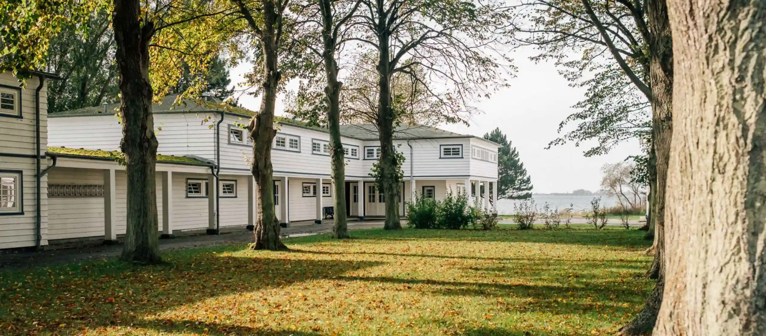 Gebäude der AOK-Klinik Rügen eingebettet in Parklandschaft mit der Ostsee im Hintergrund